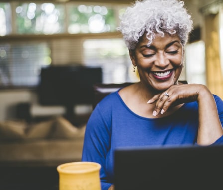 Woman at home smiling at laptop