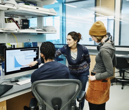 Three people looking at a graph on a computer monitor