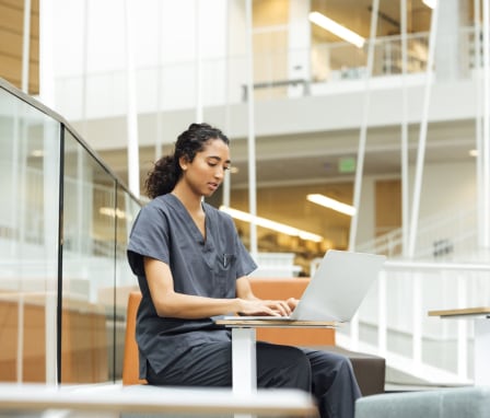 Nursing student working on a laptop at a hospital