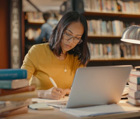 College student studying in library with laptop