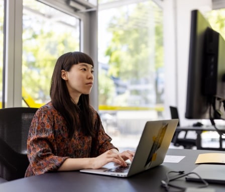 Person typing on laptop and looking at computer monitor