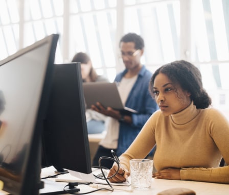 Person working at computer with people on laptops in background