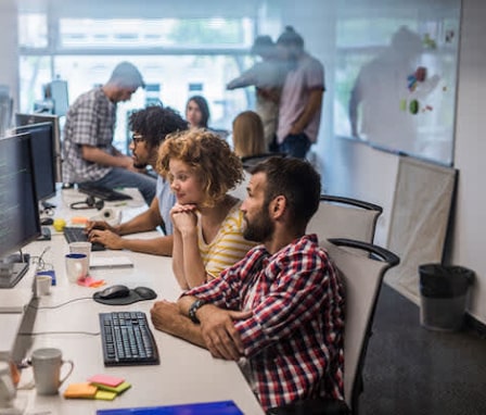 Group of colleagues working on computers together in office