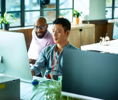 Man showing coworker how to code on his computer screen