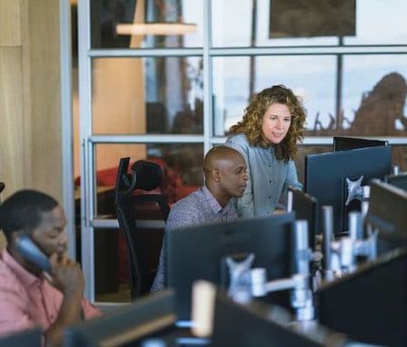 Woman helping colleague on computer