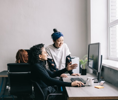 Two people working together on a desktop computer in an office