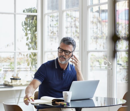 Man talking on phone and working on laptop