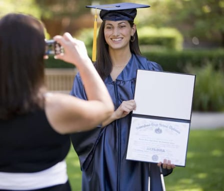 Young woman graduate holding diploma and posing for a picture