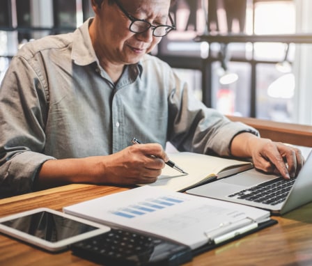 Person on laptop with a chart and calculator beside them