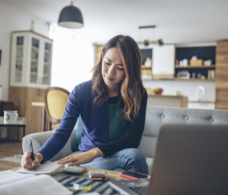 Person studying at home with laptop and book open