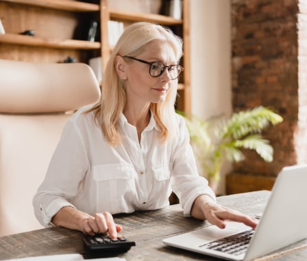 Woman typing on laptop and calculator