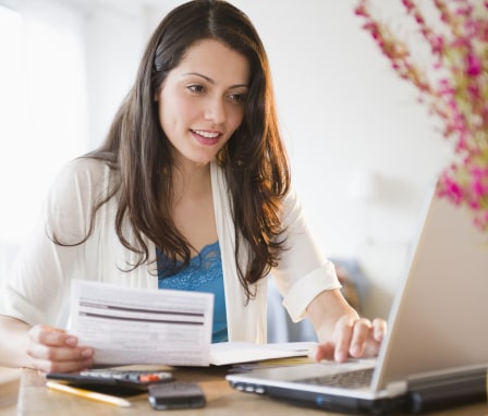 Person working on computer holding financial documents