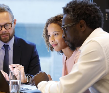 Three people working on a laptop