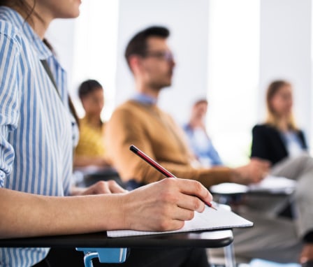 Person taking notes at a desk in a classroom