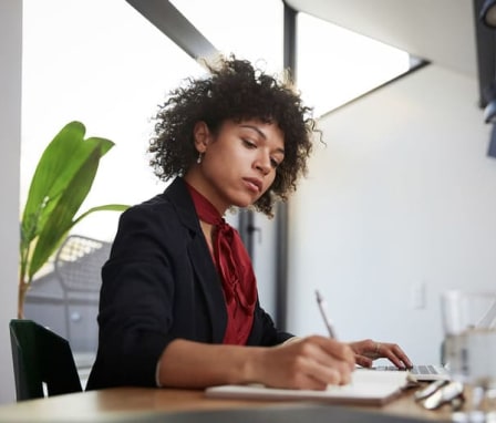 Young woman writing in notebook in office