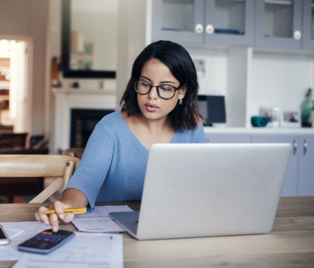 Woman working on laptop and calculator at home