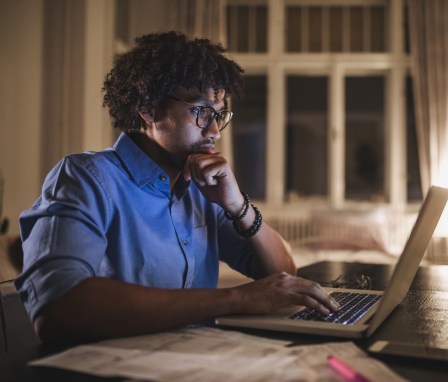 Person looking at laptop on a desk at home