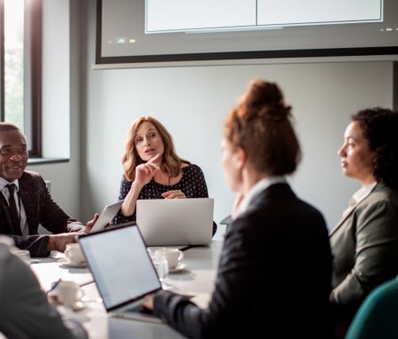 Business professionals talking around a table with their computers