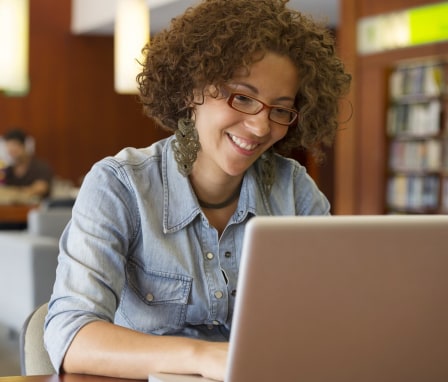 Woman typing while smiling in a library