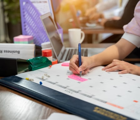 Professional writing a note on a desk calendar