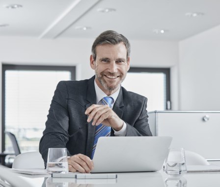 Man smiling and working on laptop in office