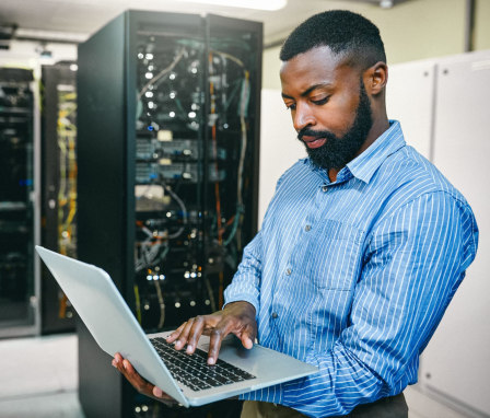 Man working on laptop in server room