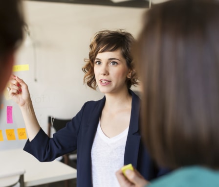 Woman presenting at whiteboard to colleagues