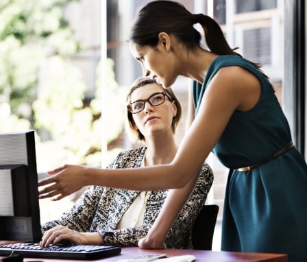 Two women working together on a computer in an office