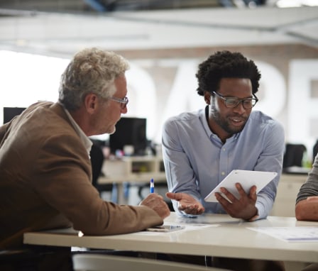 Male colleagues in a meeting, holding a tablet