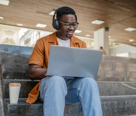 Online male student on a laptop sitting on stairs