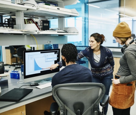Three people looking at a graph on a computer monitor