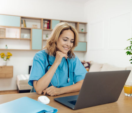 Nurse in scrubs working on laptop