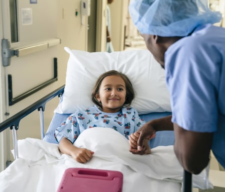 Male nurse holding the hand of a child patient before surgery