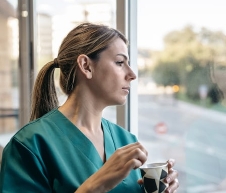 Nurse drinking coffee and looking out window