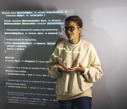 Woman programmer teaches students how to code with a console projection on the wall