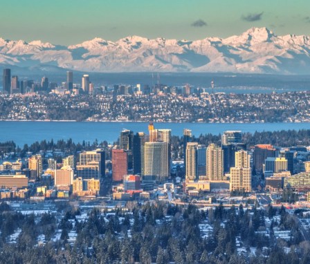 Dawn light over downtown Bellevue, with snow covered Olympic mountains, downtown Seattle, and Lake Washington in the background, in Washington state.