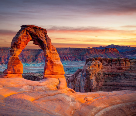 Sunset over the Delicate Arch rock formation in Arches National Park, Utah.