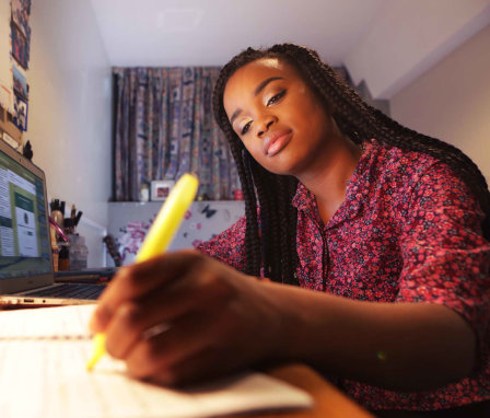Student working at desk in bedroom at night