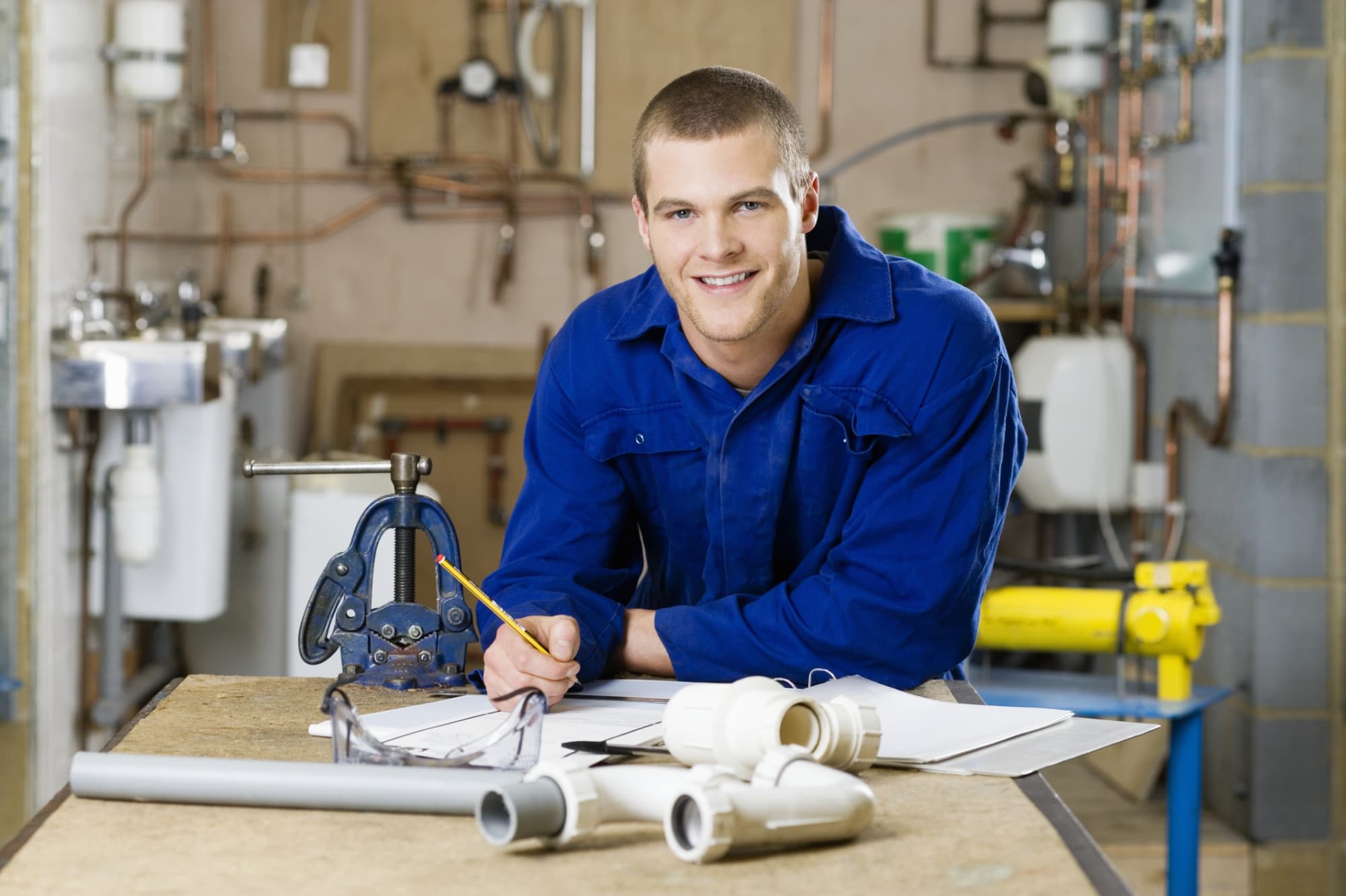 Plumber taking notes on desk with pieces of pipes