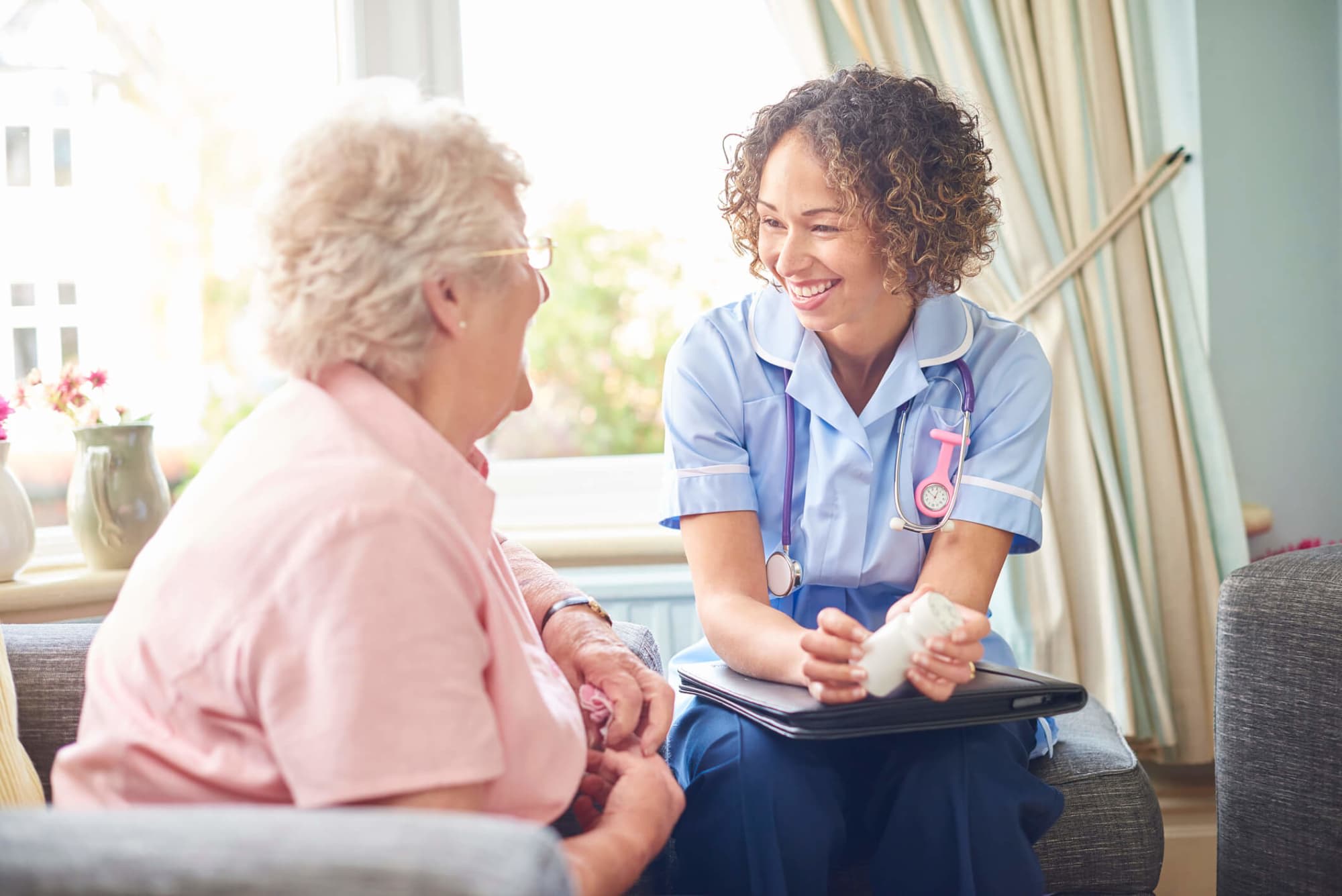 A senior woman in her home laughing with hospice nurse