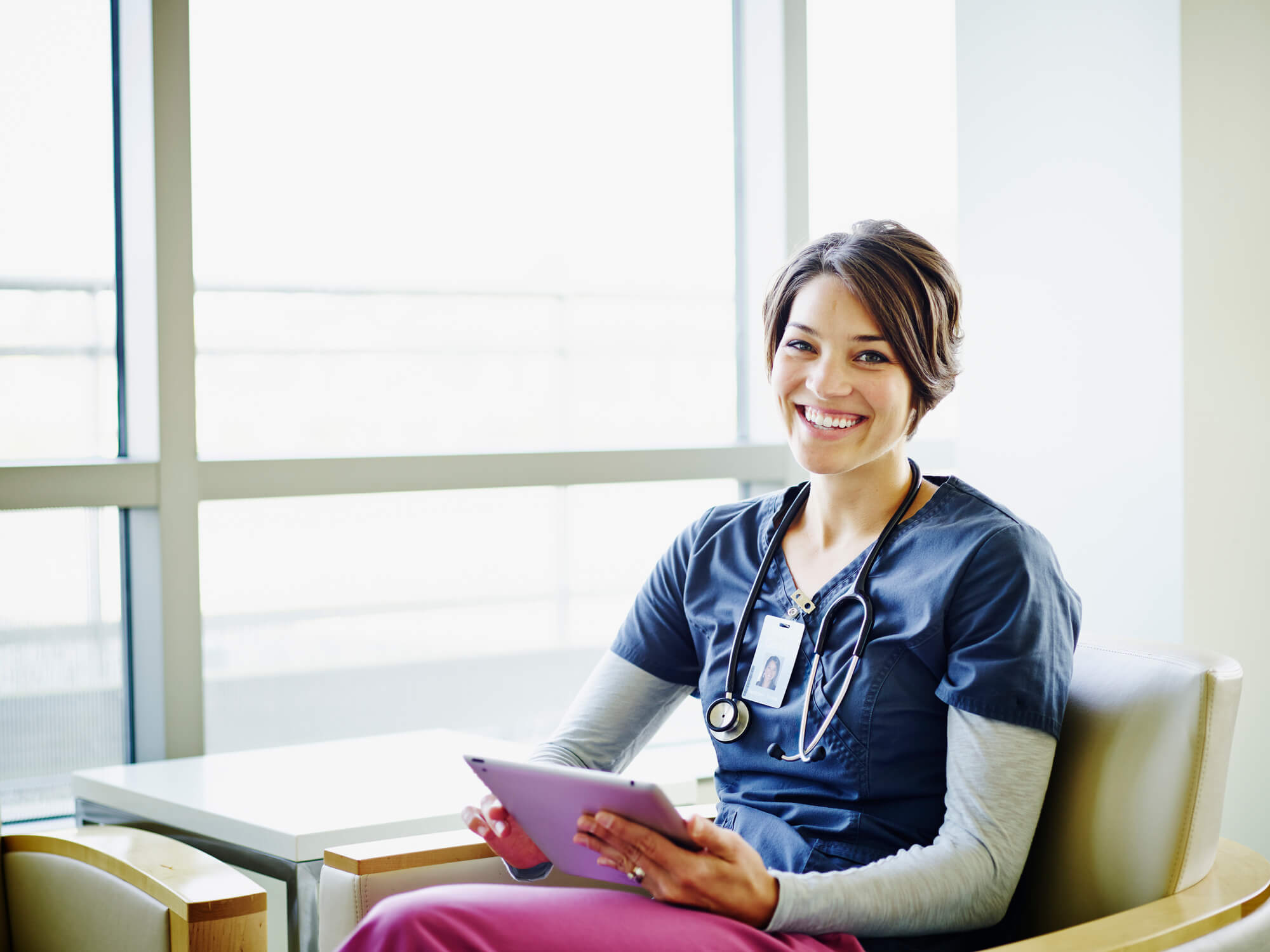 Nurse sitting in lounge with tablet