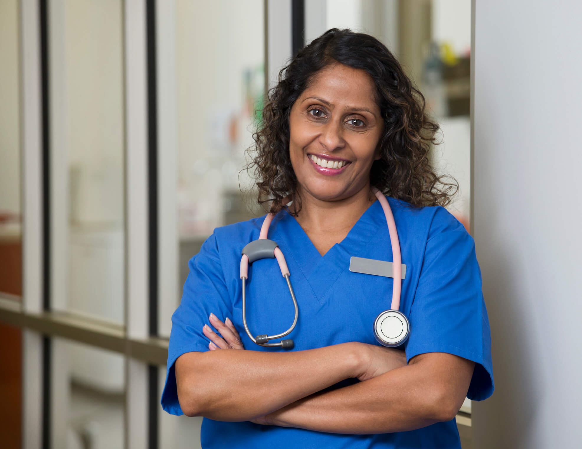 Female Indian-American nurse smiling while standing in a hospital lobby