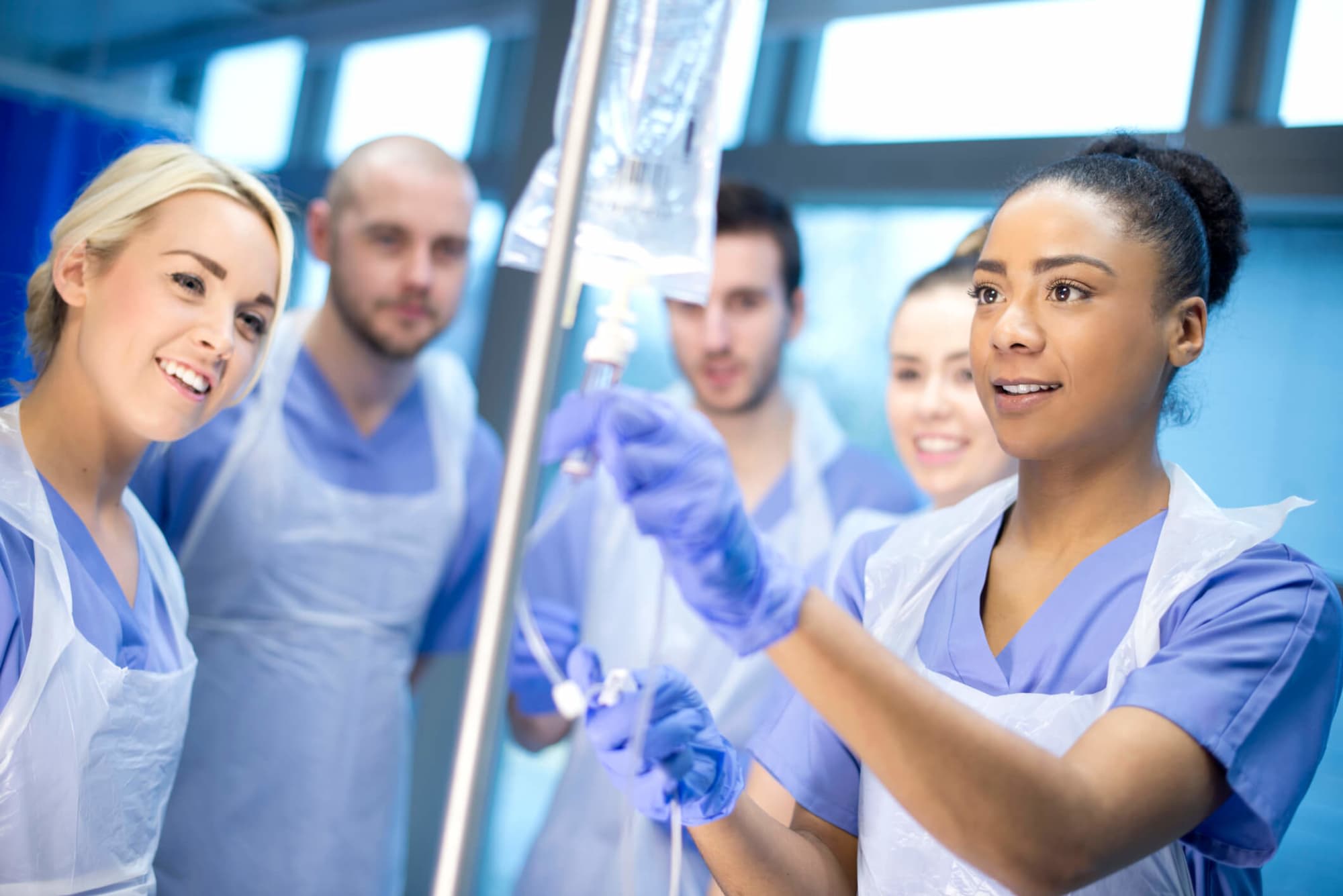 A multicultural group of nursing students practice using the IV drip during an onsite clinical.