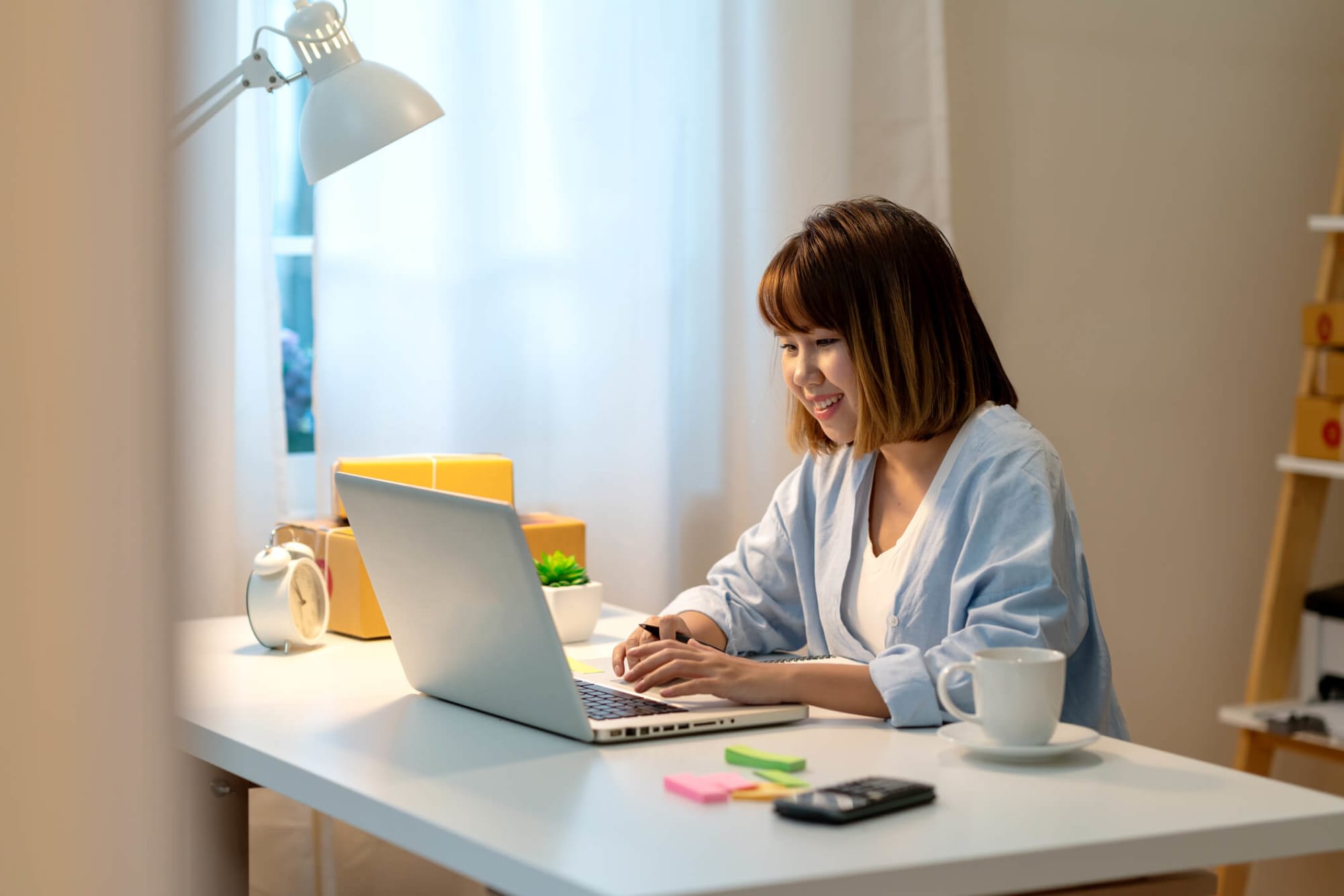 Young Asian-American female student working on completing her college applications on her laptop at home.