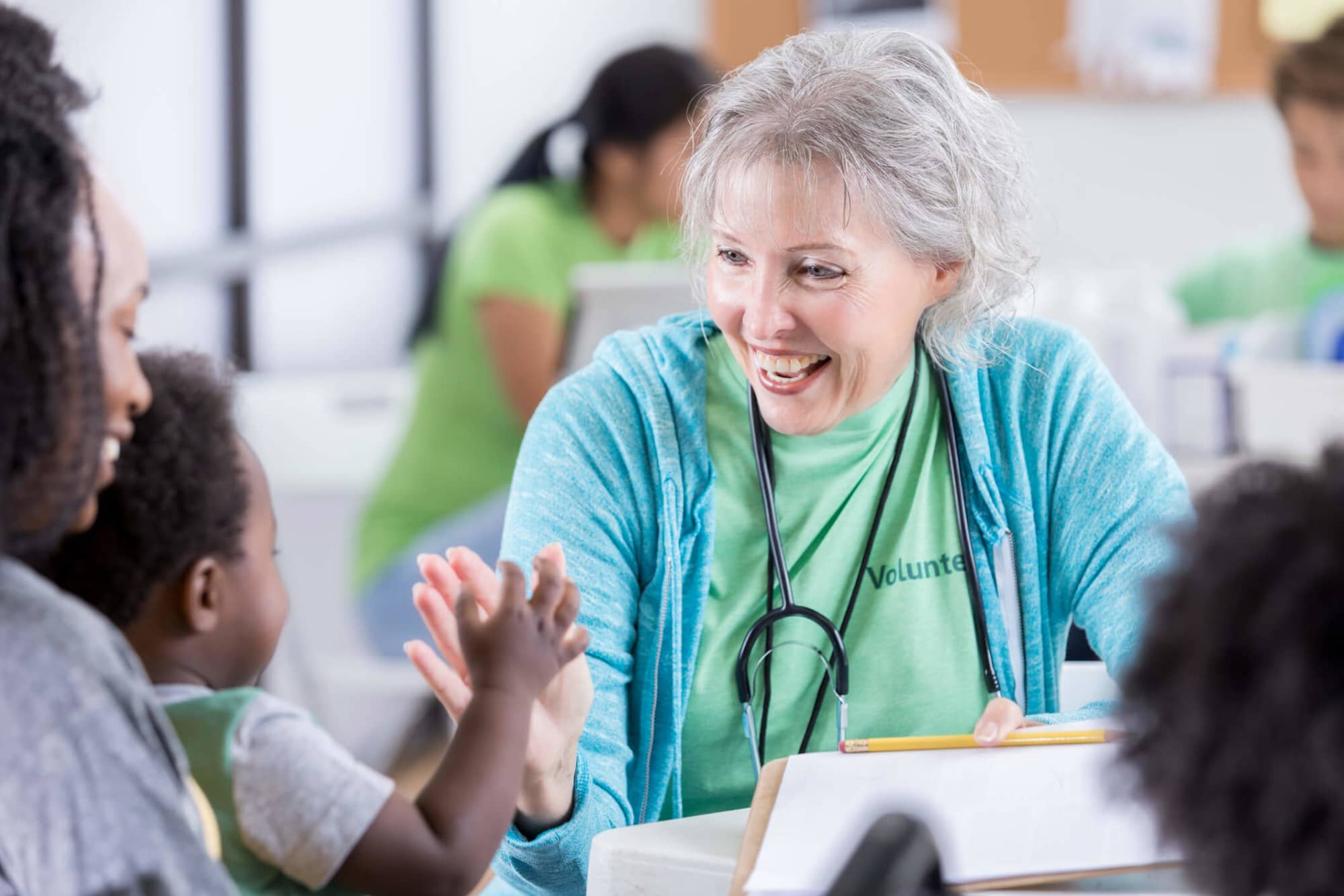 Senior woman medical volunteer smiles at baby