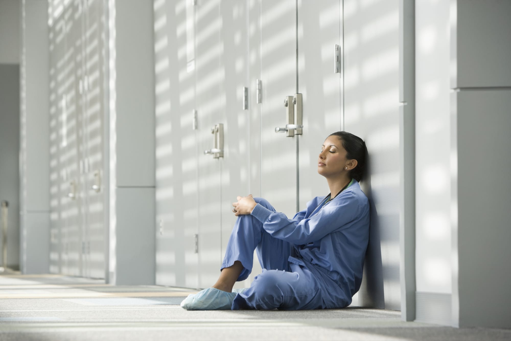 Latina nurse with eyes closed sitting on floor