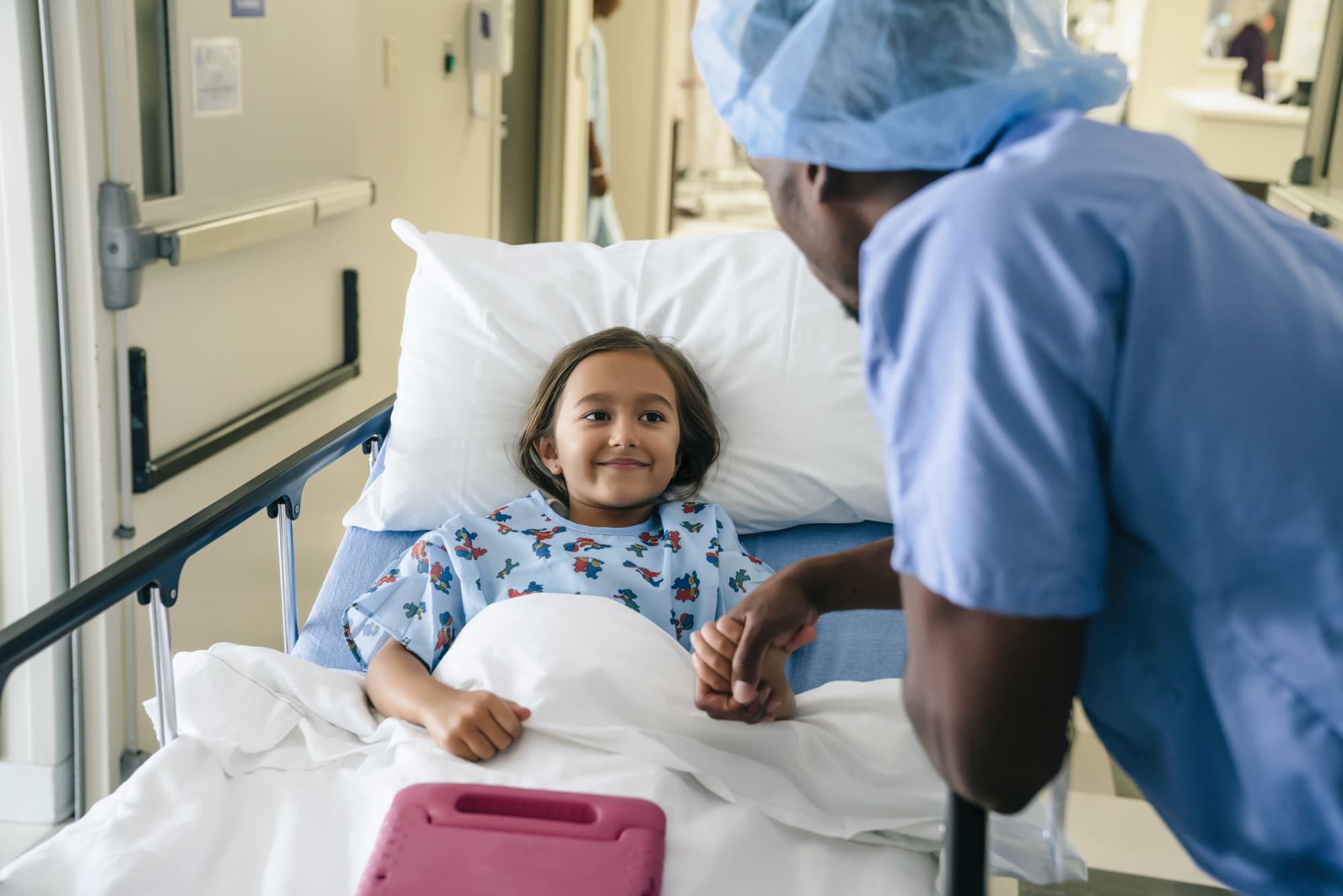 Male nurse holding the hand of a child patient before surgery