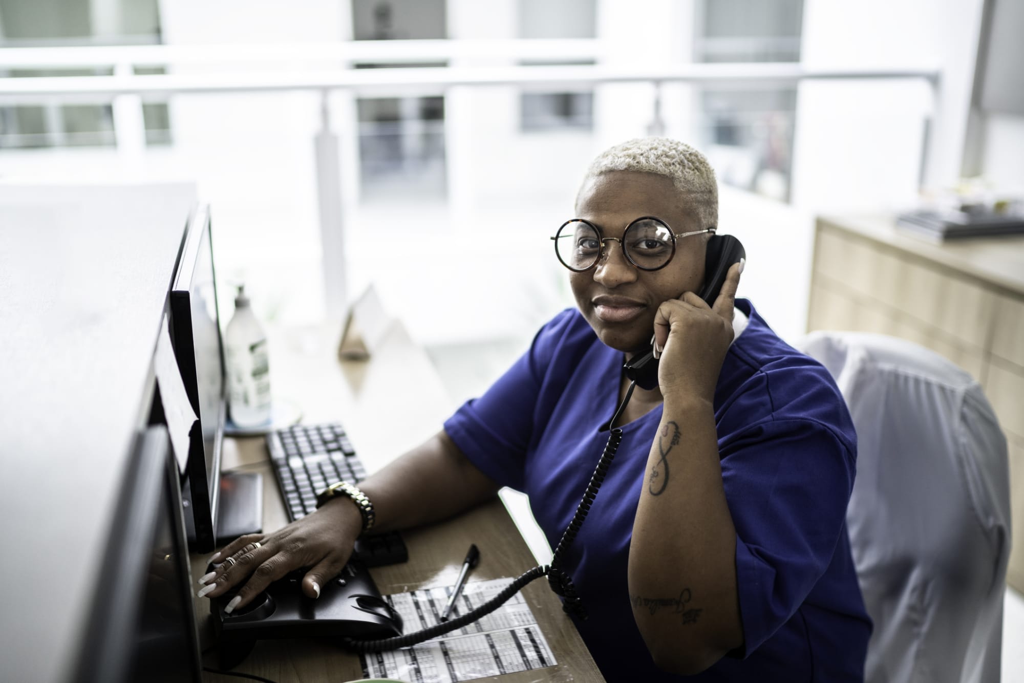 Medical assistant talking on the phone at a desk