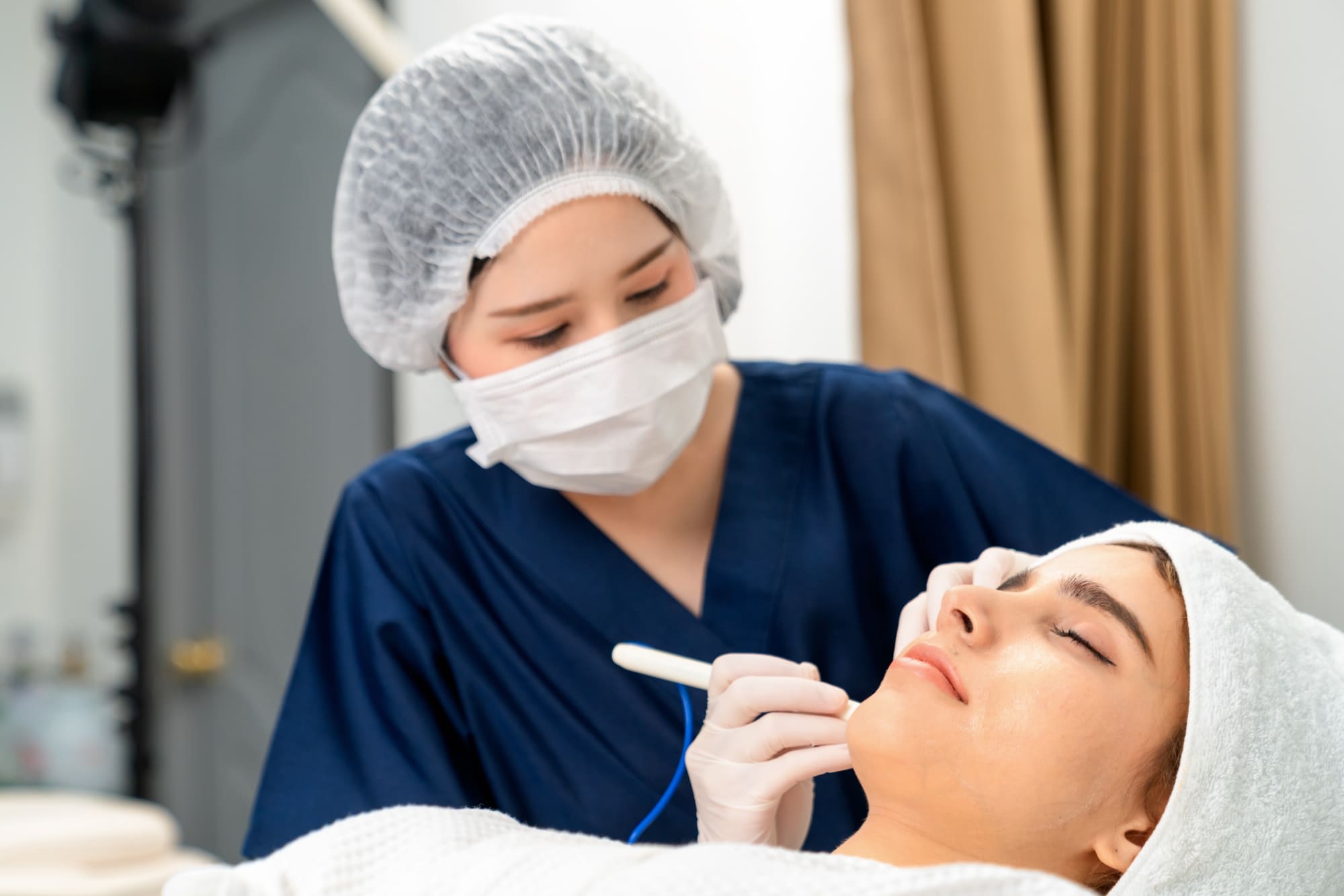 Cosmetologist cleaning or peeling face of young woman in Cosmetologically clinic.