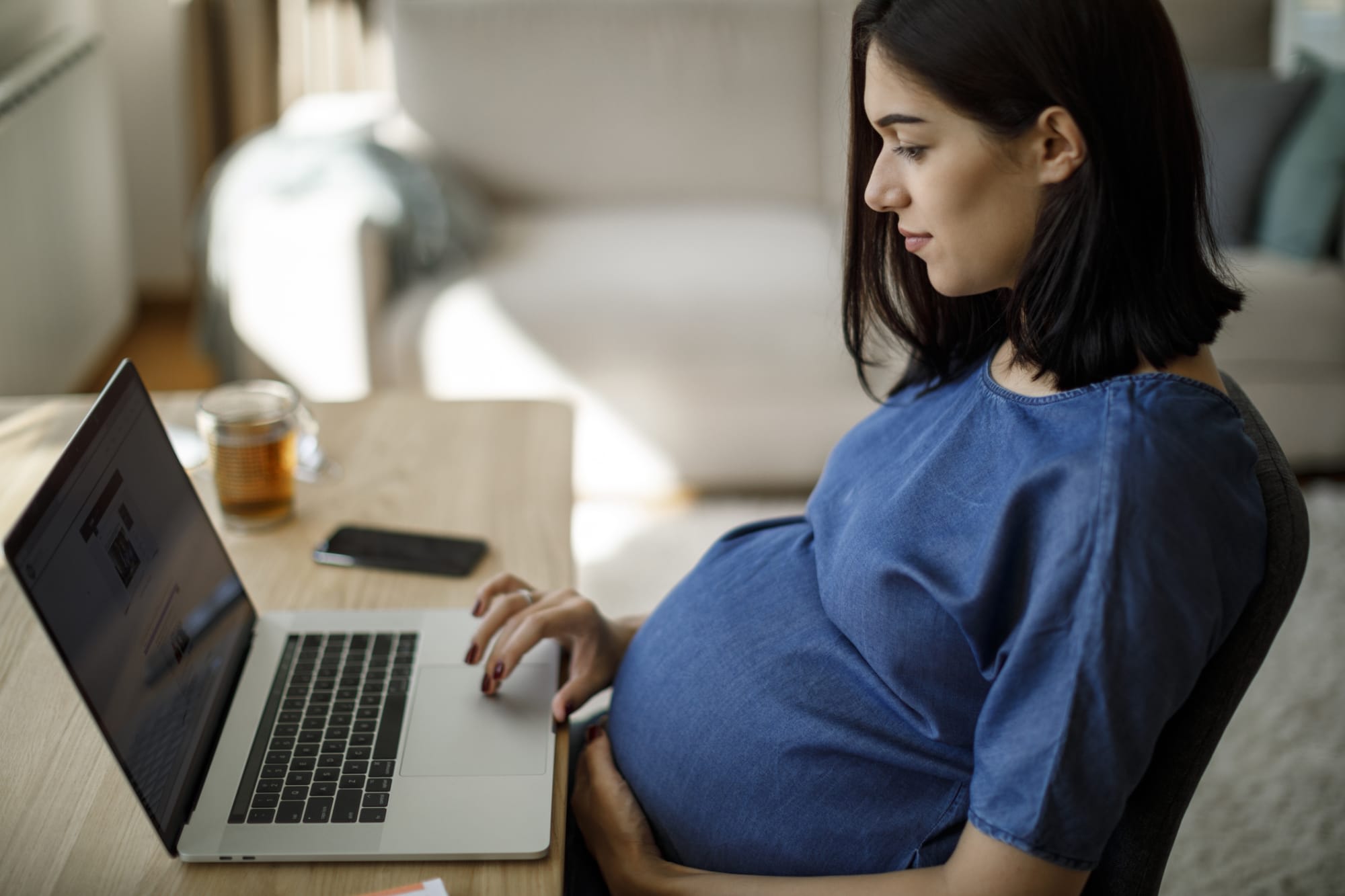 Pregnant person using laptop at a desk